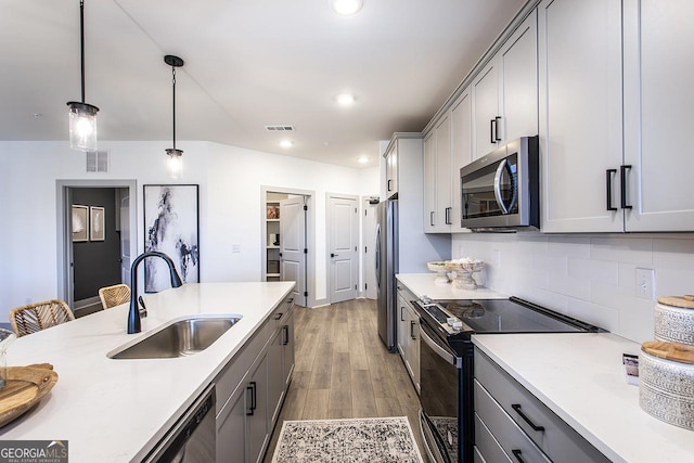 kitchen with decorative light fixtures, stainless steel appliances, gray cabinets, and sink