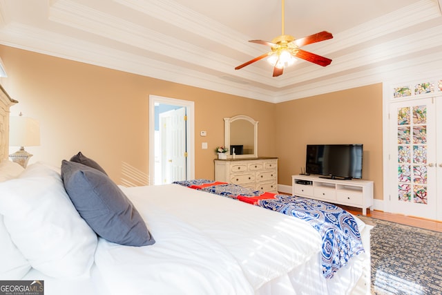 bedroom with hardwood / wood-style flooring, ceiling fan, ornamental molding, and a tray ceiling