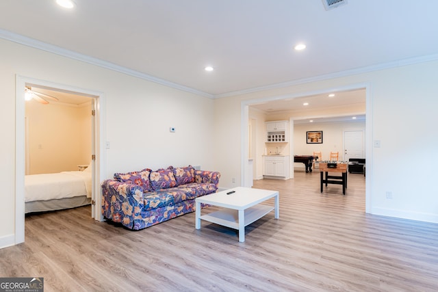 living room with crown molding, ceiling fan, and light wood-type flooring