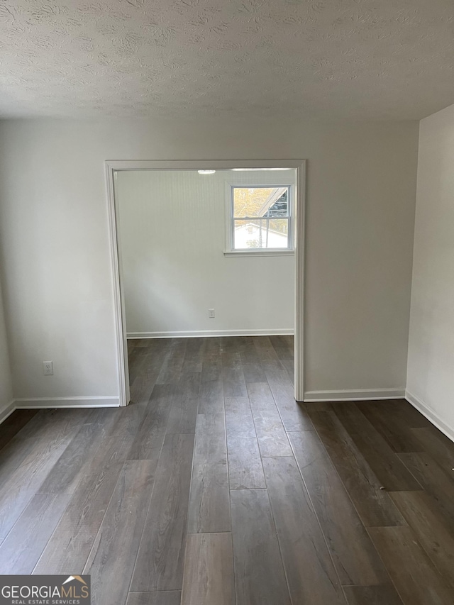 spare room featuring dark hardwood / wood-style floors and a textured ceiling