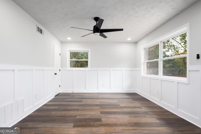 spare room featuring a textured ceiling, dark hardwood / wood-style floors, and plenty of natural light