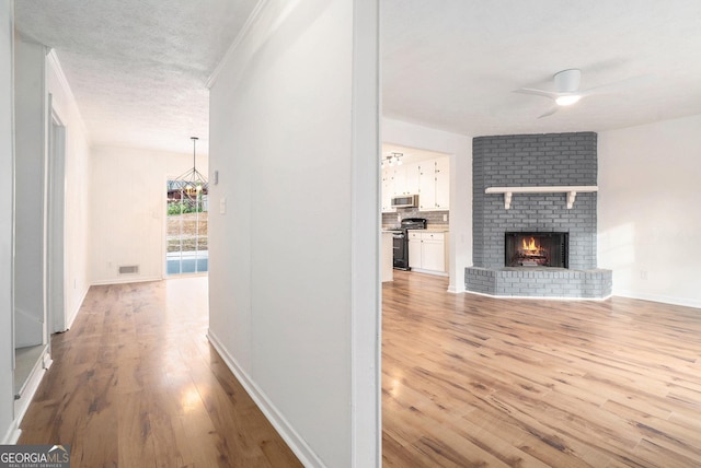 hallway featuring light hardwood / wood-style floors, crown molding, and a textured ceiling