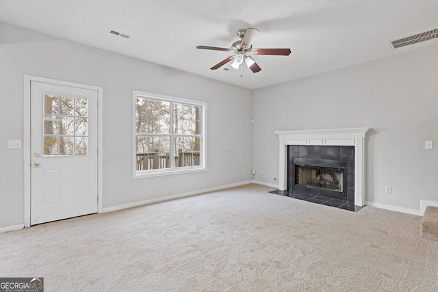 unfurnished living room featuring a tile fireplace, ceiling fan, and carpet