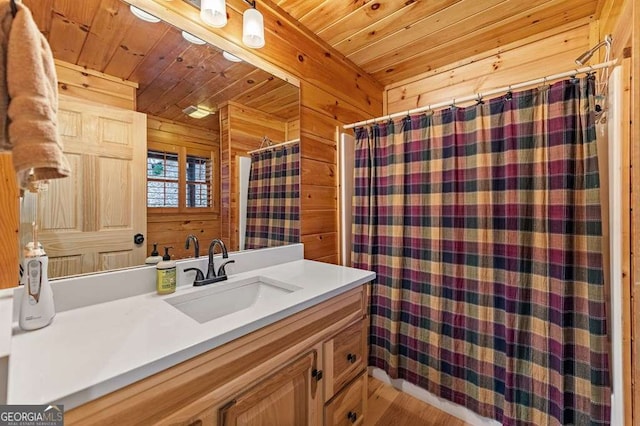 bathroom featuring vanity, wood ceiling, and wood walls