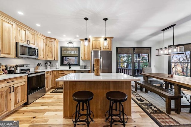 kitchen with pendant lighting, stainless steel appliances, sink, and a kitchen island