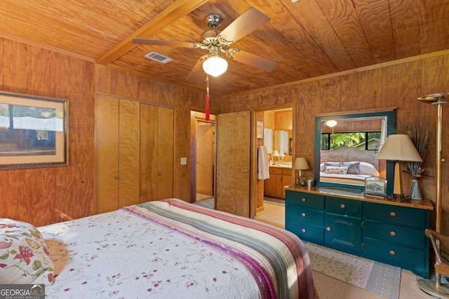 bedroom with ceiling fan, ensuite bathroom, wooden walls, a closet, and wood ceiling