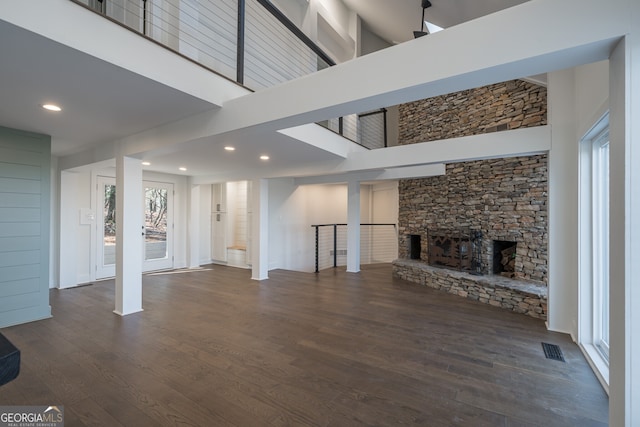 unfurnished living room with a fireplace, a high ceiling, and dark hardwood / wood-style flooring