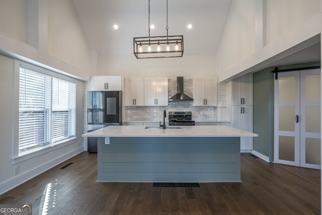 kitchen with high vaulted ceiling, wall chimney range hood, sink, electric stove, and a barn door