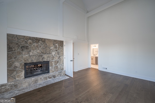 unfurnished living room featuring a high ceiling, dark hardwood / wood-style floors, and a stone fireplace