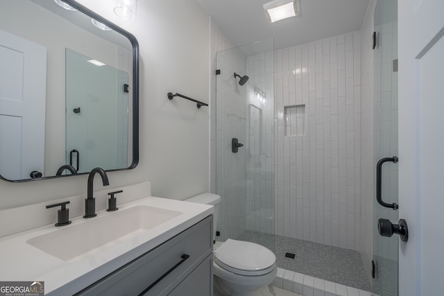 bathroom featuring vanity, a shower with shower door, and toilet