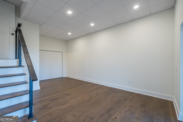 basement featuring a paneled ceiling and dark hardwood / wood-style floors