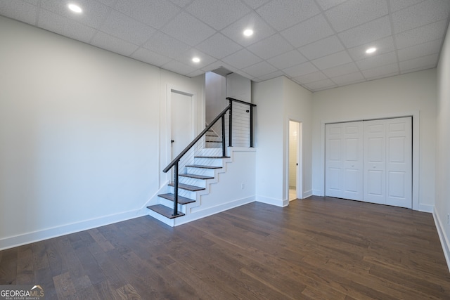 basement featuring a paneled ceiling and dark wood-type flooring