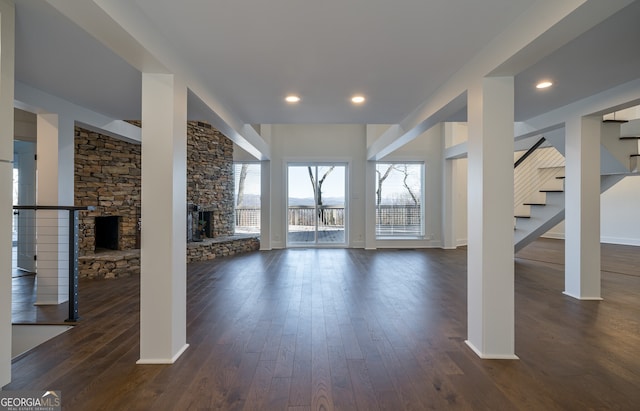 unfurnished living room with dark hardwood / wood-style flooring and a stone fireplace