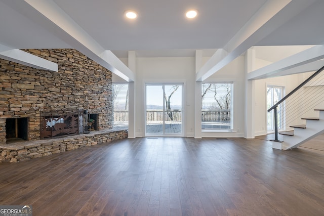 unfurnished living room with dark hardwood / wood-style flooring and a stone fireplace