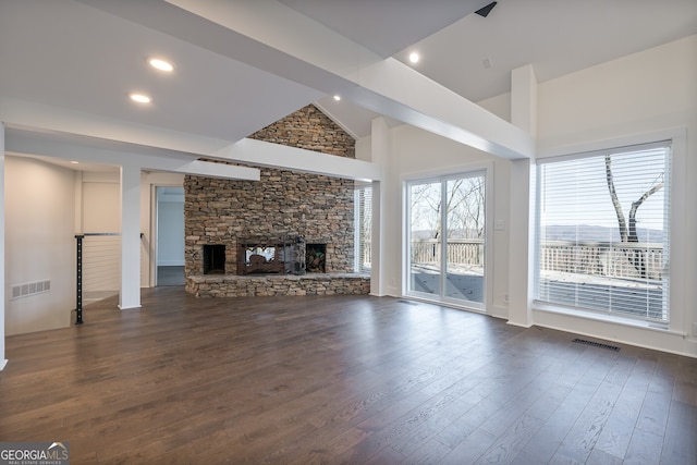 unfurnished living room with high vaulted ceiling, dark hardwood / wood-style floors, and a stone fireplace