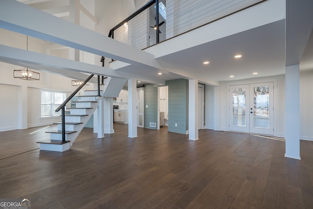 unfurnished living room featuring a chandelier, french doors, dark wood-type flooring, and a high ceiling