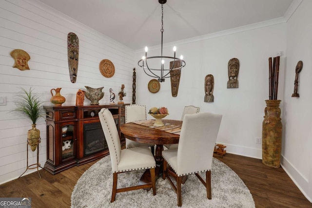 dining space with wood walls, crown molding, dark wood-type flooring, and a chandelier