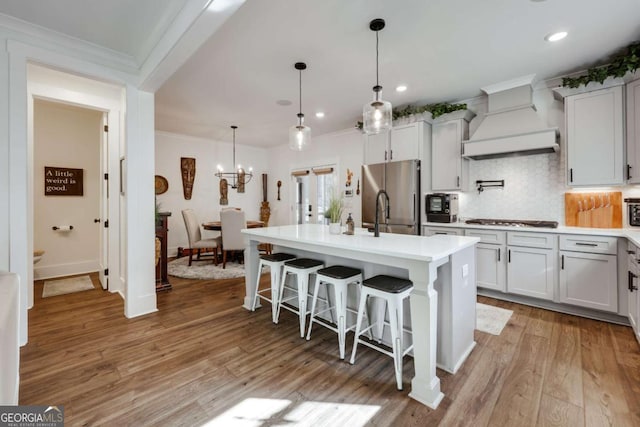 kitchen featuring white cabinets, custom exhaust hood, stainless steel appliances, and light hardwood / wood-style flooring