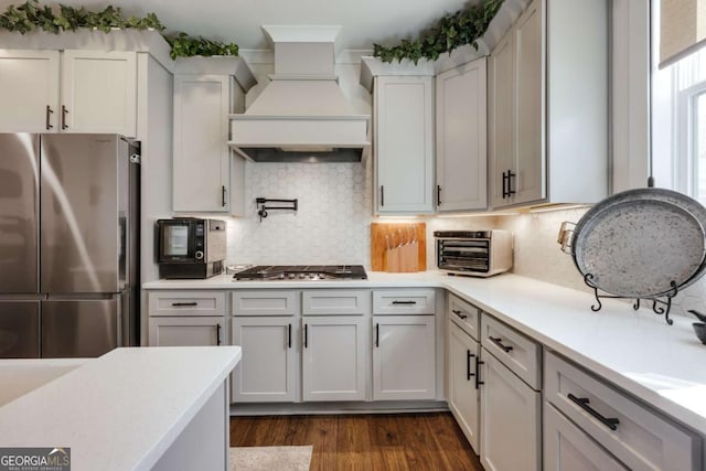 kitchen featuring premium range hood, tasteful backsplash, dark hardwood / wood-style flooring, and stainless steel appliances