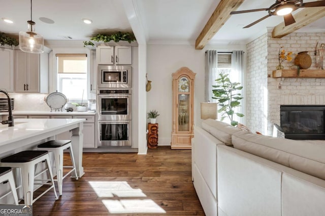 interior space with beamed ceiling, dark hardwood / wood-style flooring, a brick fireplace, and a healthy amount of sunlight