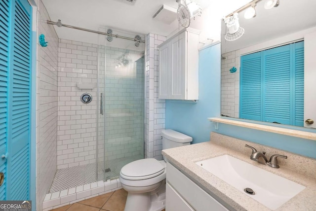 bathroom featuring tile patterned flooring, vanity, toilet, and a shower with door