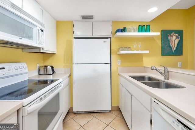 kitchen with light tile patterned flooring, white appliances, white cabinetry, and sink