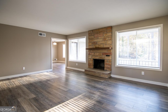 unfurnished living room with a fireplace, dark hardwood / wood-style flooring, and a wealth of natural light