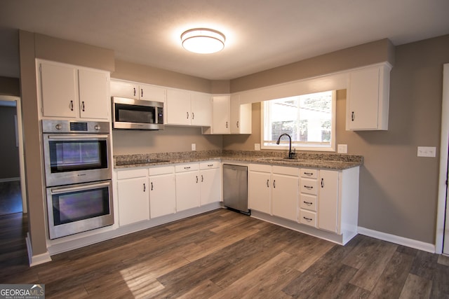 kitchen with appliances with stainless steel finishes, dark hardwood / wood-style flooring, white cabinetry, and sink