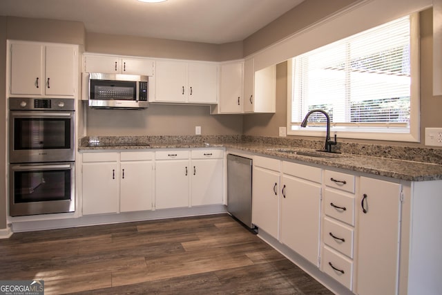 kitchen featuring dark hardwood / wood-style flooring, white cabinetry, sink, and appliances with stainless steel finishes