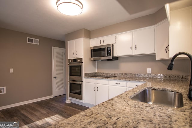 kitchen featuring dark wood-type flooring, sink, light stone counters, white cabinetry, and stainless steel appliances