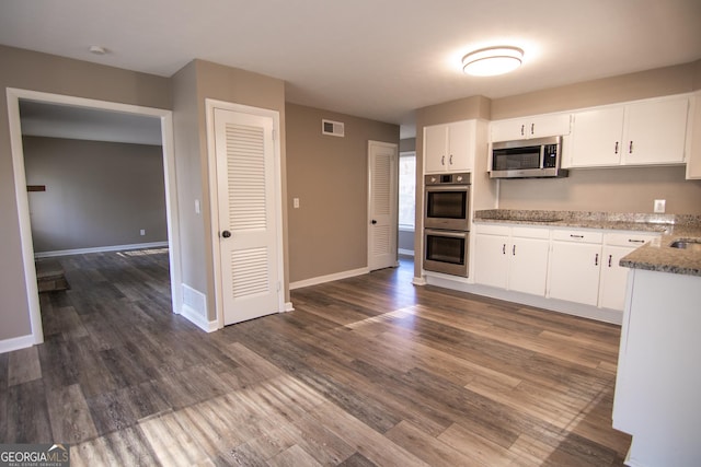 kitchen with light stone counters, dark hardwood / wood-style flooring, white cabinetry, and stainless steel appliances