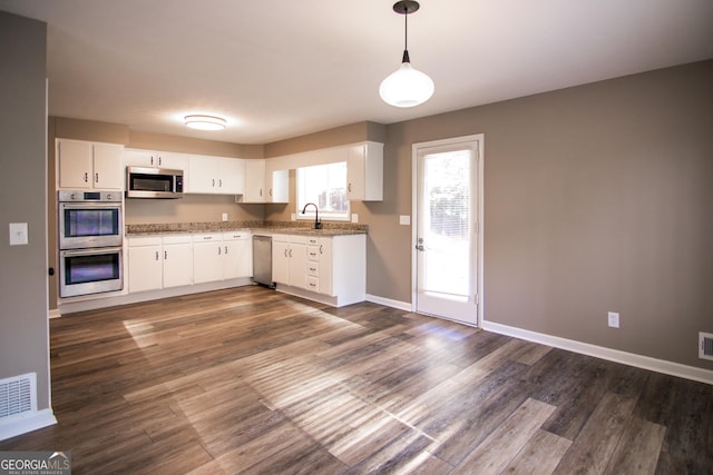 kitchen featuring sink, hanging light fixtures, stainless steel appliances, dark hardwood / wood-style flooring, and white cabinets