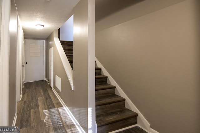 stairs featuring a textured ceiling and hardwood / wood-style flooring