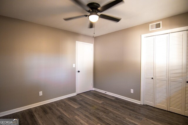 unfurnished bedroom with ceiling fan, dark wood-type flooring, and a closet