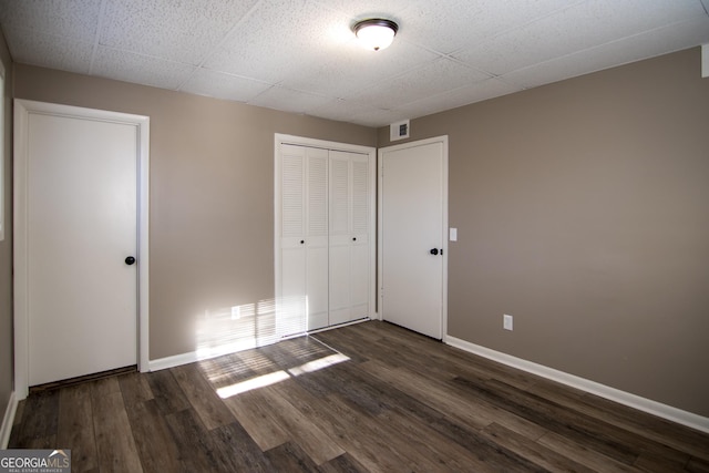 unfurnished bedroom featuring a closet and dark wood-type flooring