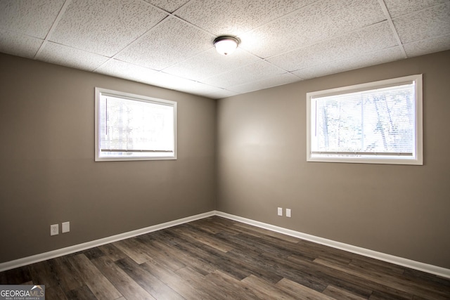 unfurnished room with a paneled ceiling and dark hardwood / wood-style flooring