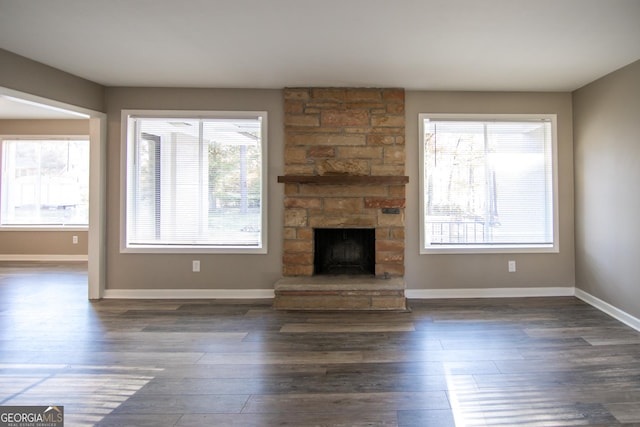 unfurnished living room featuring plenty of natural light, dark hardwood / wood-style floors, and a fireplace