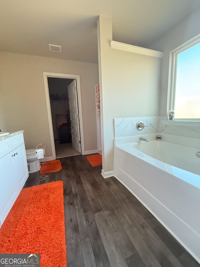 bathroom featuring a tub, toilet, vanity, and hardwood / wood-style flooring