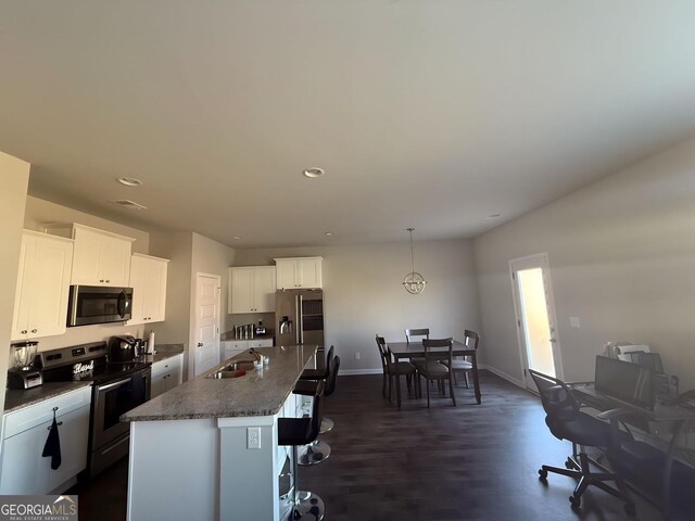 kitchen with sink, dark hardwood / wood-style flooring, an island with sink, white cabinets, and appliances with stainless steel finishes