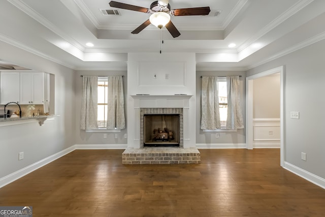 unfurnished living room featuring a raised ceiling, ceiling fan, crown molding, sink, and dark hardwood / wood-style floors