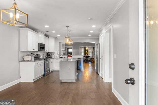 kitchen with hanging light fixtures, appliances with stainless steel finishes, a kitchen island, light stone counters, and white cabinetry