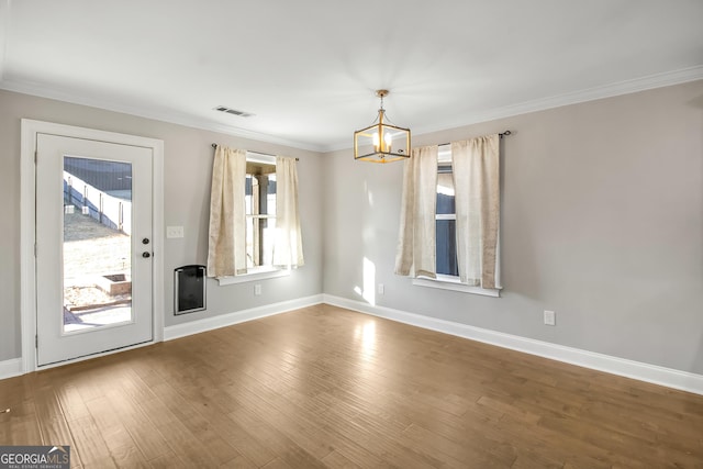 spare room with hardwood / wood-style flooring, an inviting chandelier, and crown molding