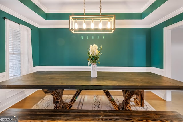 unfurnished dining area with wood-type flooring, crown molding, and a tray ceiling