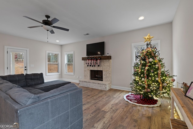 living room with a brick fireplace, ceiling fan, and hardwood / wood-style flooring