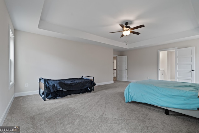 carpeted bedroom with connected bathroom, a tray ceiling, and ceiling fan