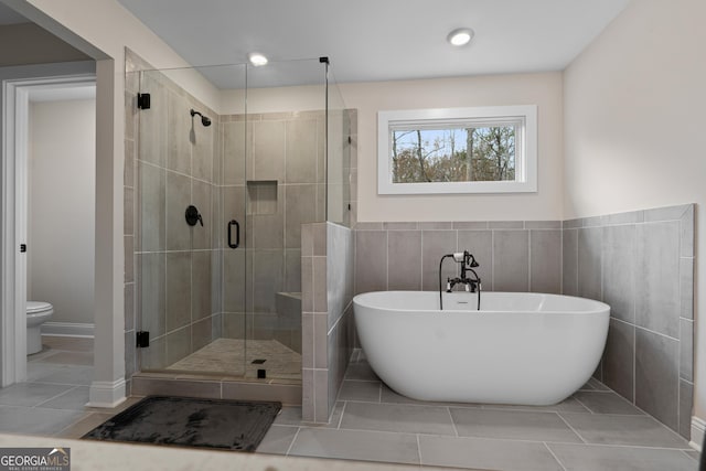 bathroom with tile patterned flooring, toilet, tile walls, and independent shower and bath