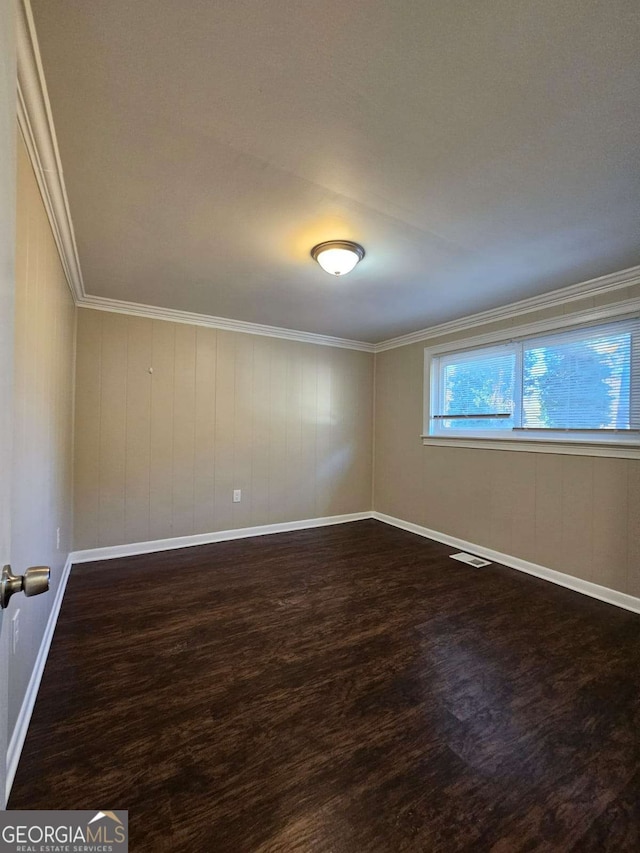 unfurnished room featuring crown molding, wooden walls, and dark wood-type flooring