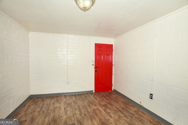 unfurnished room with dark wood-type flooring and brick wall