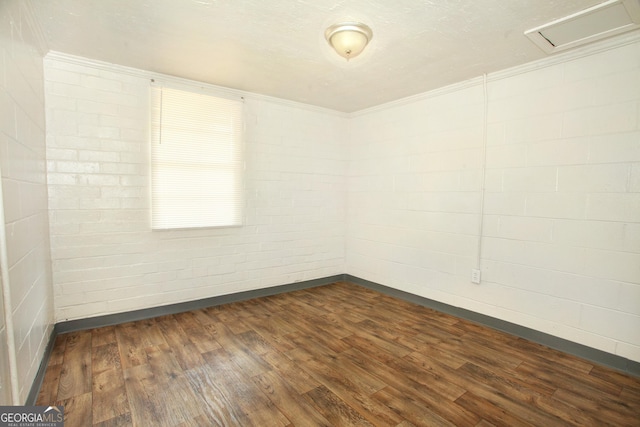 spare room featuring dark wood-type flooring and brick wall