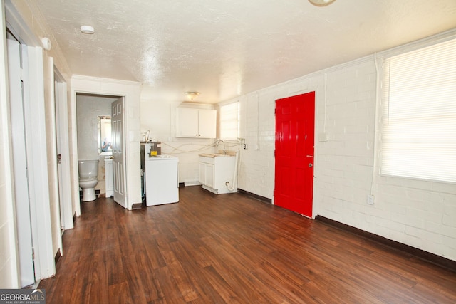 interior space featuring white cabinets, dark wood-type flooring, washer / clothes dryer, and a textured ceiling